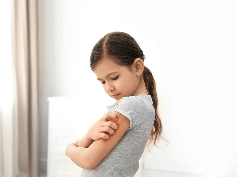 Young girl scratching her itchy arm.